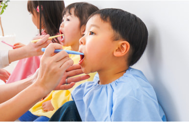 スタッフが子供の歯磨きを補助している。